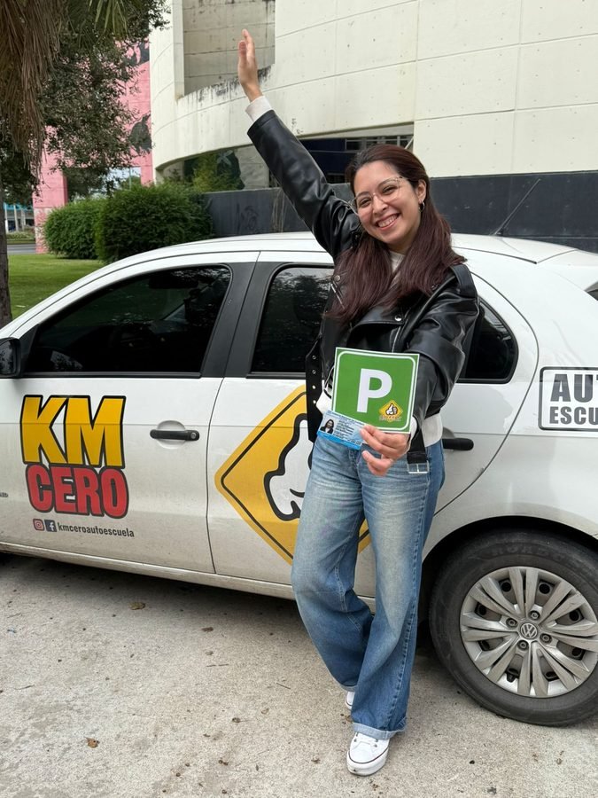 María Patiño festejando con su licencia junto al auto de Km Cero Auto Escuela